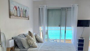 A bedroom with a bed, a bedside table, a TV, and a view of the sea. - BEACH LOFT with fantastic view over the Mediterranean and Palamos. (Sant Antoni de Calonge)