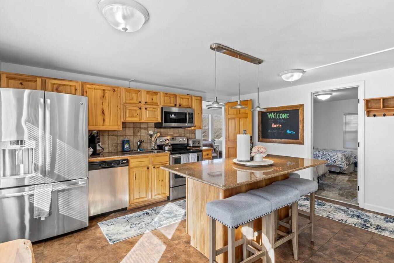 Una cocina moderna con armarios de madera, electrodomésticos de acero inoxidable y una isla central con taburetes de bar.
