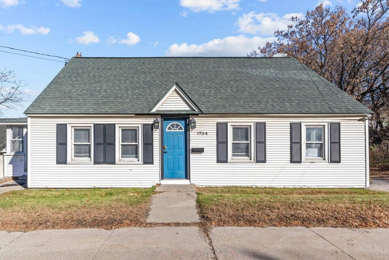 A single-story house with a gabled roof, a blue front door, and a small porch area.
