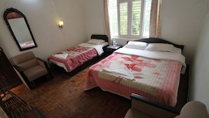 Habitación de hotel con dos camas individuales, piso de madera, una silla, una mesita de noche y un espejo.