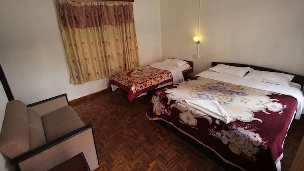 Una habitación con cama, sofá y ventana con cortinas.