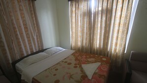 Una habitación de hotel con cama, cortinas y una silla.