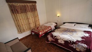 Una habitación con dos camas, un sofá y suelo de madera con estampado de espiga.