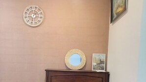 A piano with a chair in front, a wall clock, and a framed picture. - Hôtel Le Celtic (Montlucon)