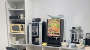A café with a white interior, a microwave, a coffee machine, and a menu board. - Hôtel Le Celtic (Montlucon)
