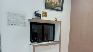 A room with a television on a wooden stand, a framed landscape painting above it, a small sign reading "Accueil Reception," and a map on the wall. - Hôtel Le Celtic (Montlucon)