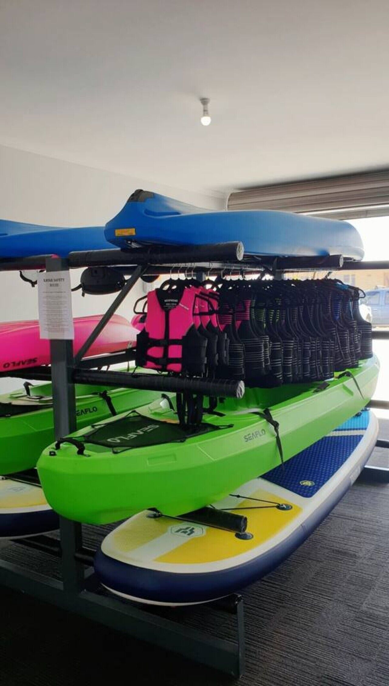A room with a ceiling fan, a bed with a blue canopy, and a green inflatable raft on a stand.
