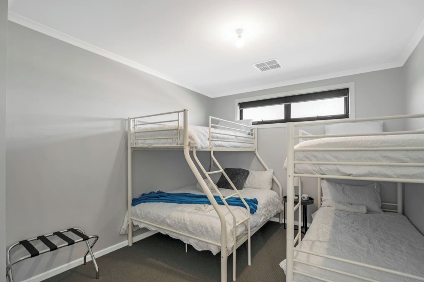Een kamer met stapelbedden, een raam en een plafondlamp.