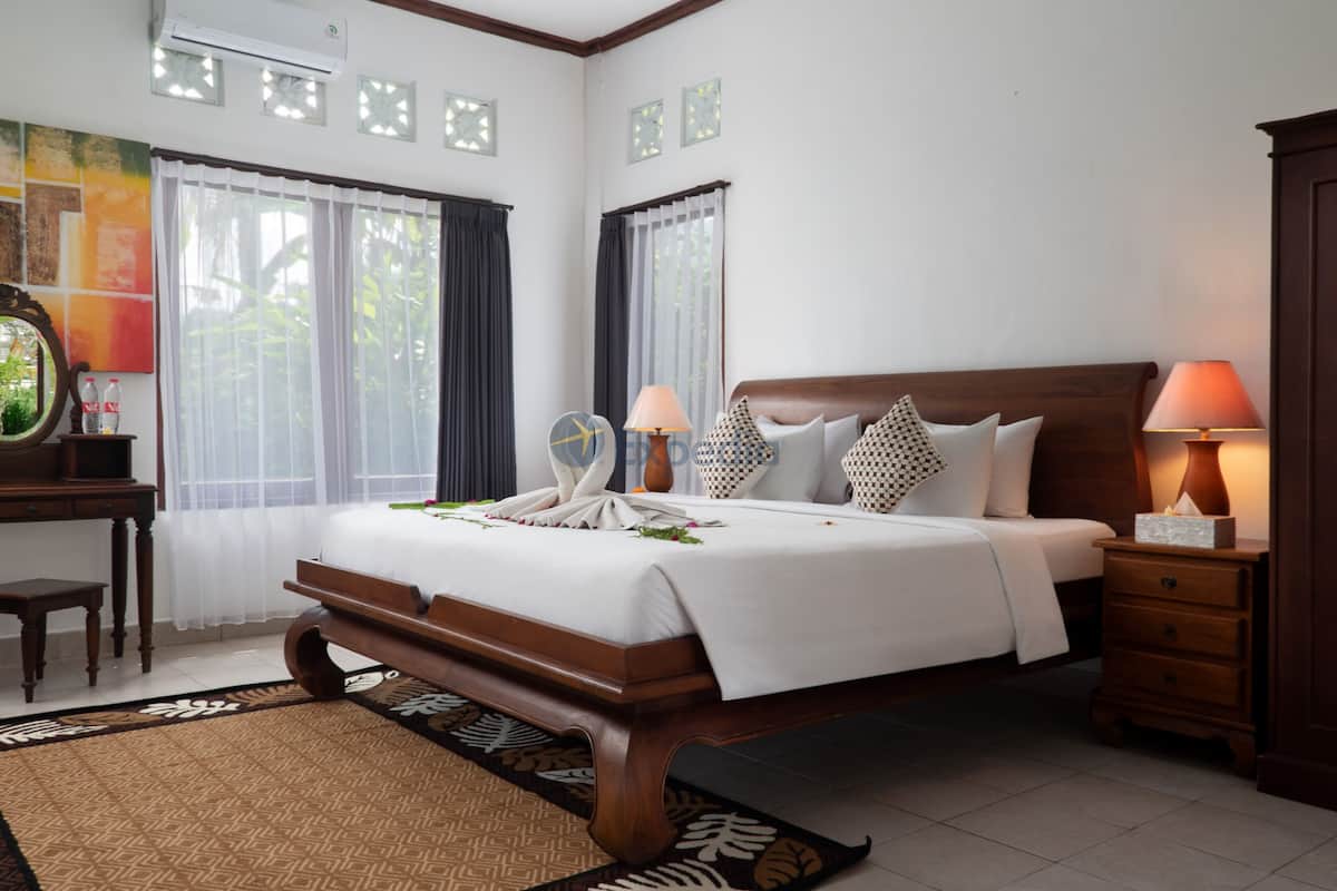 A neatly arranged bedroom with a wooden bed, bedside lamps, a nightstand, and a desk with a mirror and decorative items.