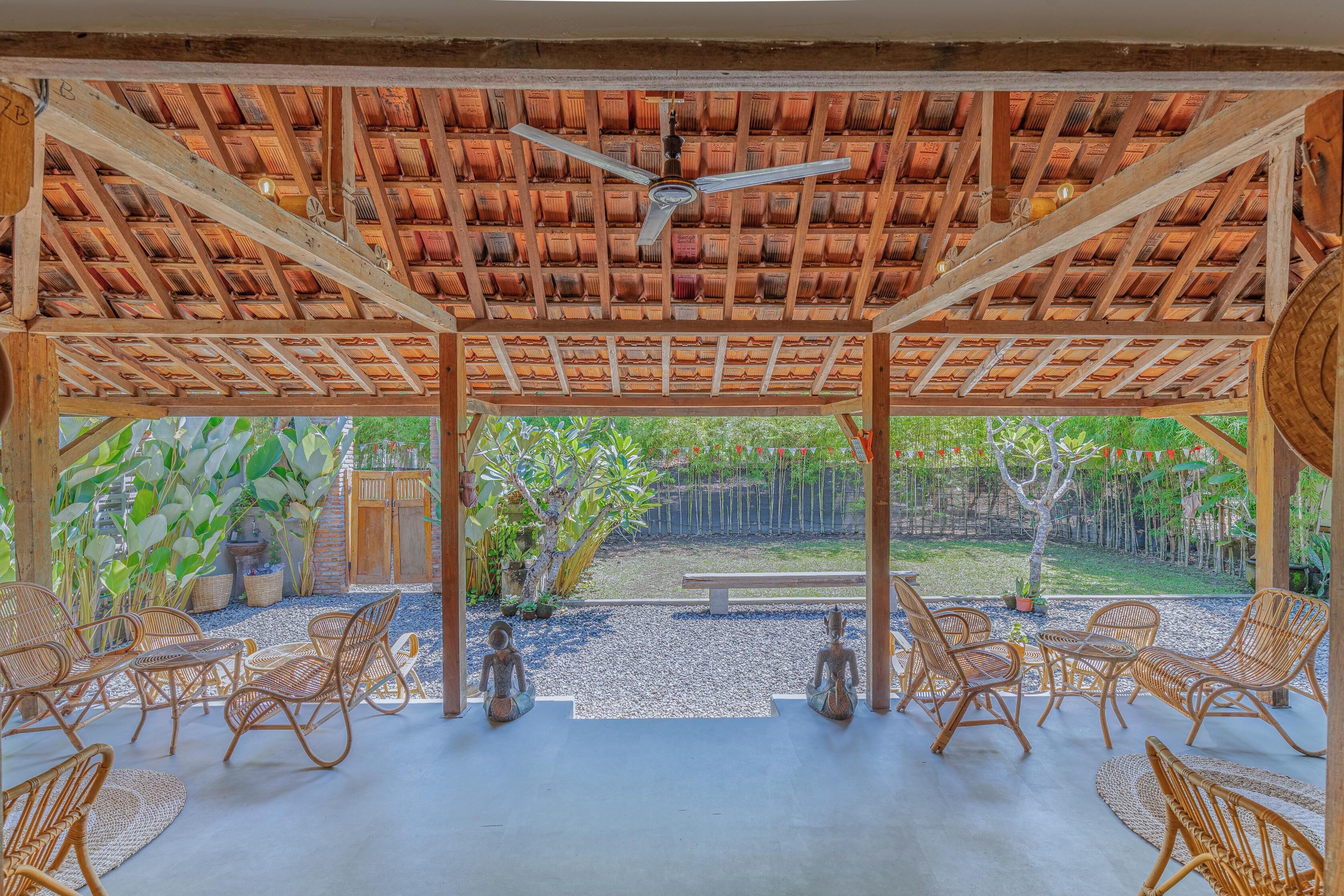 A covered outdoor seating area with wicker furniture and a ceiling fan.