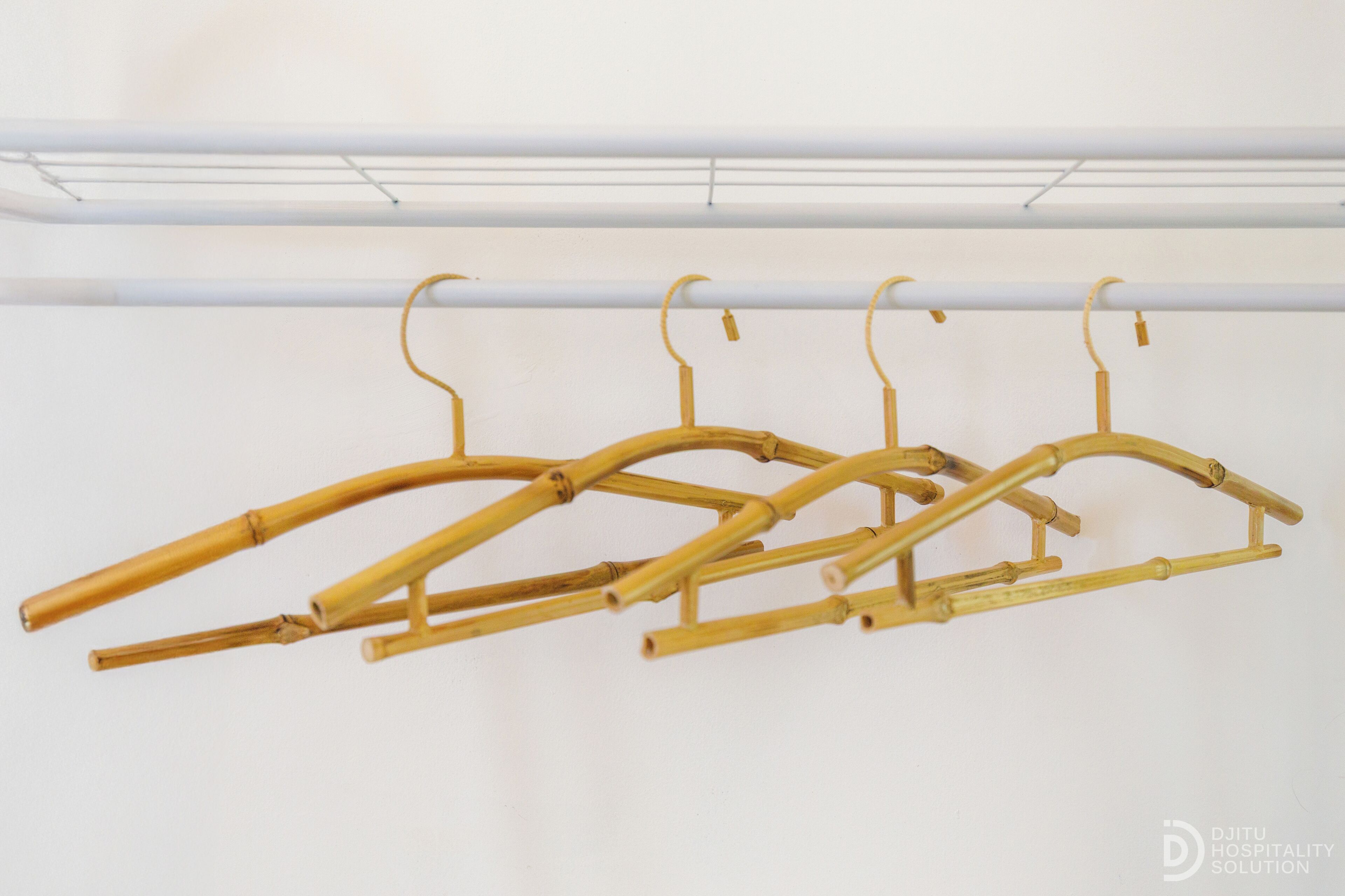 A set of bamboo hangers hanging on a white wall.