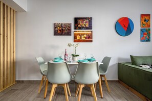 A dining area with a table set for two, chairs, a green sofa, and wall art.