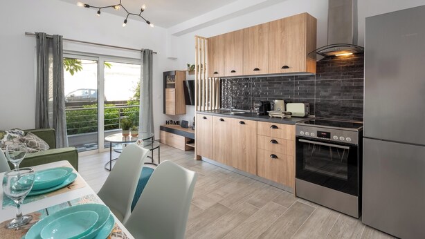 A modern kitchen with wooden cabinets, a black backsplash, and stainless steel appliances. - Nice n Cosy Apartment in Rhodes Town (Rodos)