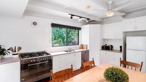 Une cuisine moderne avec des meubles blancs, une cuisinière et un coin repas comprenant une table et des chaises.