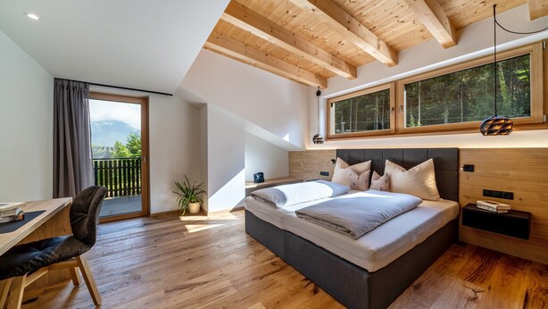 A bedroom with a bed, a desk, a chair, a window, and a balcony. - Wiesgut Gala Apartment with Mountain View, Balcony, and Wi-Fi (Tesimo)