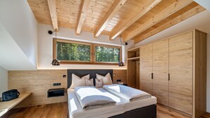 A bedroom with a wooden ceiling, a large bed, a wardrobe, and a window with a view of trees. - Wiesgut Gala Apartment with Mountain View, Balcony, and Wi-Fi (Tesimo)