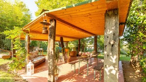 Un porche cubierto al aire libre con vigas de madera, un banco y una mesa.