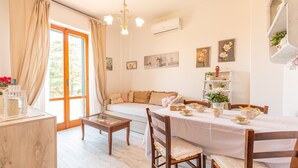 Una sala acogedora con un sofá, una mesa de comedor dispuesta para el té y una estantería con objetos decorativos.