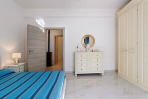 A bedroom with a bed, a dresser, a wardrobe, and a mirror.