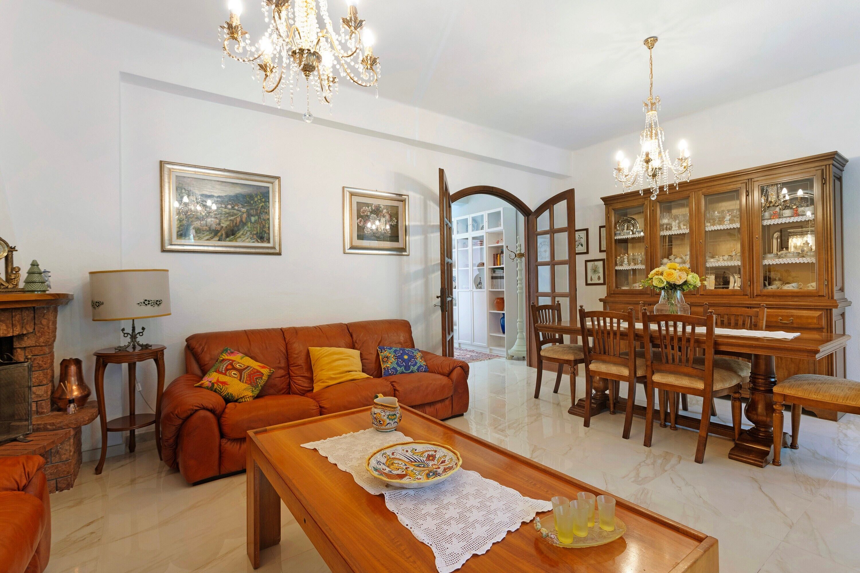 A living room with a sofa, coffee table, and a dining area with chairs and a cabinet.
