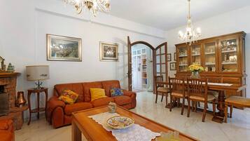 A living room with a sofa, coffee table, and a dining area with chairs and a cabinet.