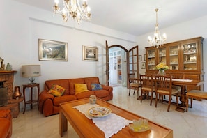 A living room with a sofa, coffee table, and a dining area with chairs and a cabinet.