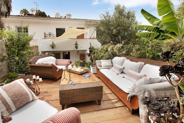 Eine Terrasse mit Korbmöbeln, einer Couch und einem Esstisch.