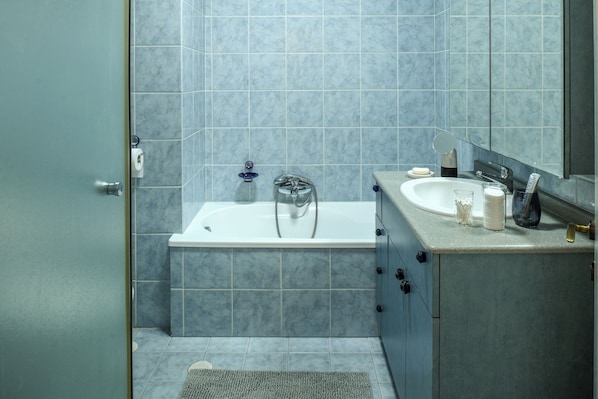 A bathroom with a bathtub, a sink, and a mirror.