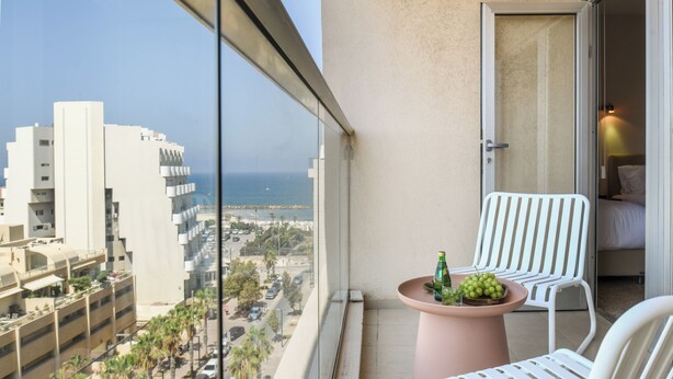 A balcony with a table, two chairs, and a view of the city and ocean. - 3BR SeaView Apt by the Beach by SeaNRent (Herzliya)