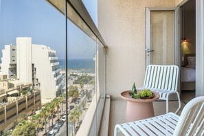 A balcony with a table, two chairs, and a view of the city and ocean.