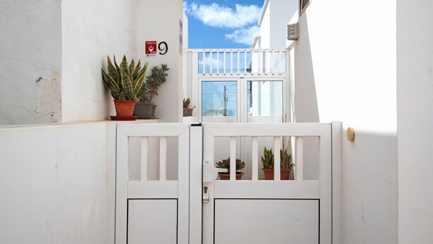 A white gate with a balcony, potted plants, and a clear sky. - Vacation Home "Casa Tipica Canaria" with Sea View, Private Terrace & Wi-Fi (Playa Honda)