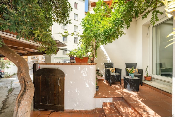 Une terrasse avec des sièges d’extérieur, une porte en bois et des plantes en pot.