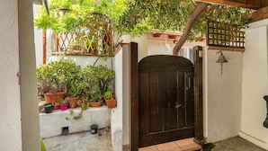 A wooden door, potted plants, and a small step leading to a covered area. - Apartment "In Casetta" with Private Garden and Wi-Fi (Cagliari)
