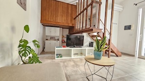 A living room with a TV, a staircase, and a potted plant. - Apartment "In Casetta" with Private Garden and Wi-Fi (Cagliari)