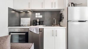 Una cocina moderna con electrodomésticos de acero inoxidable, armarios blancos y una salpicadura de mármol.