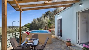 Un espacio al aire libre techado con piscina, mesa de comedor, sillas y plantas en macetas.