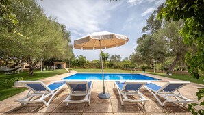Una piscina con sillones de descanso y una sombrilla.