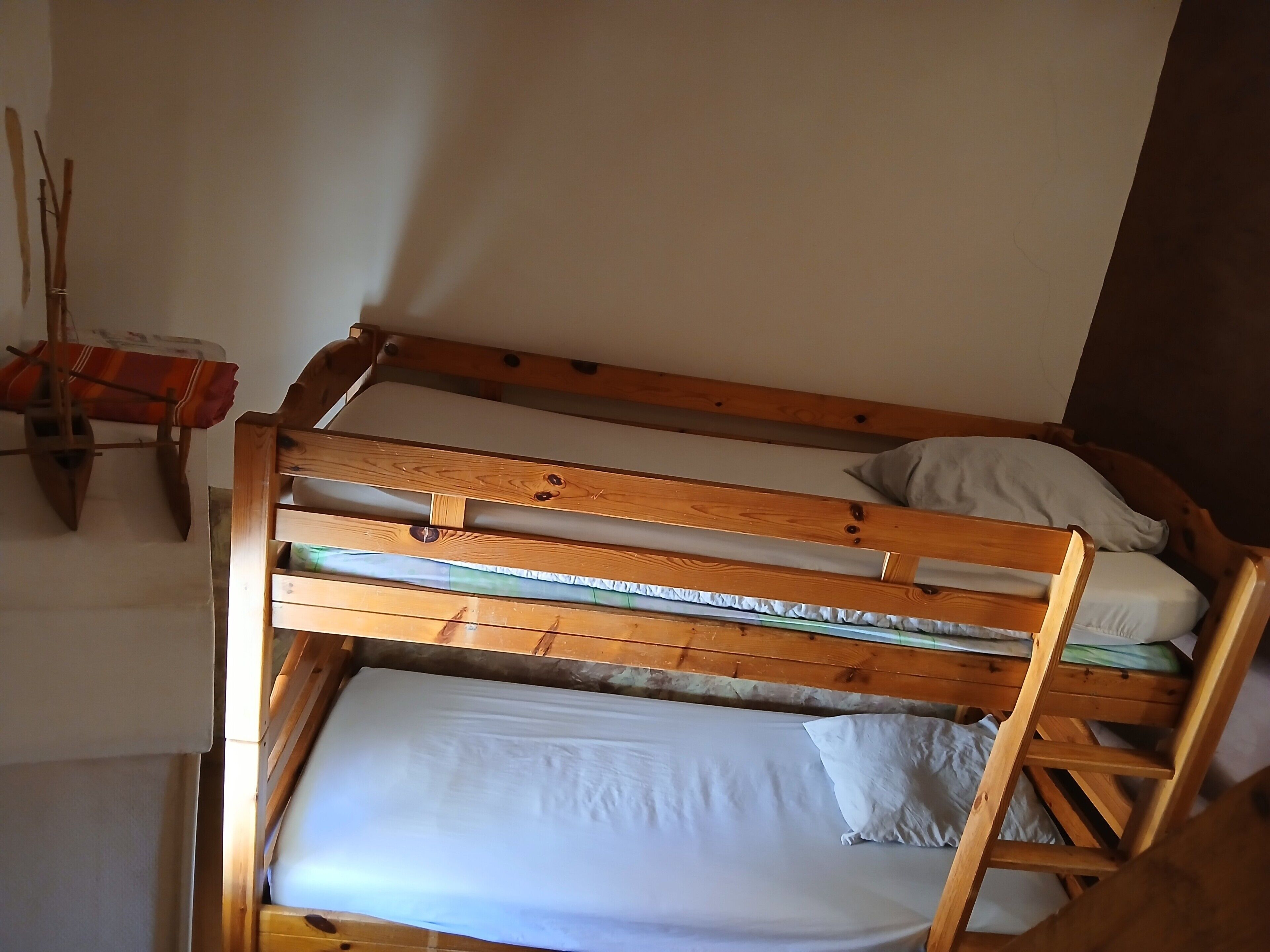 A bunk bed with a wooden frame, a white mattress, and a pillow.
