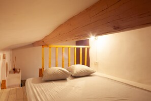 A bedroom with a wooden headboard, a bed with white bedding, and a small bedside table.