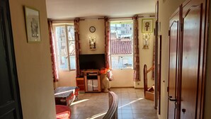 A living room with a TV, a clock, and a window with curtains. - Apartment 'Loft Americain Centre Ville' with Wi-Fi (Marseille)