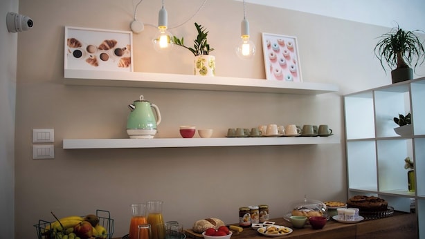 A kitchen with white shelves displaying mugs, a kettle, and a fruit basket. - Dimora Donna Dora (San Martino in Pensilis)
