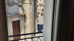 A view from a balcony with a wrought iron railing, overlooking a street with buildings and a clear blue sky. - Dimora Donna Dora (San Martino in Pensilis)