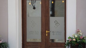 A double wooden door with frosted glass panels, each displaying a logo and name. - Dimora Donna Dora (San Martino in Pensilis)