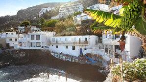 A coastal town with white buildings, a beach, and a cliff.