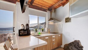 A kitchen with a view of the sea, wooden cabinets, a countertop, and a sink.