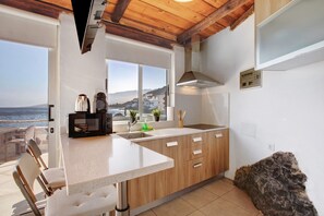 A kitchen with a view of the sea, wooden cabinets, a countertop, and a sink.