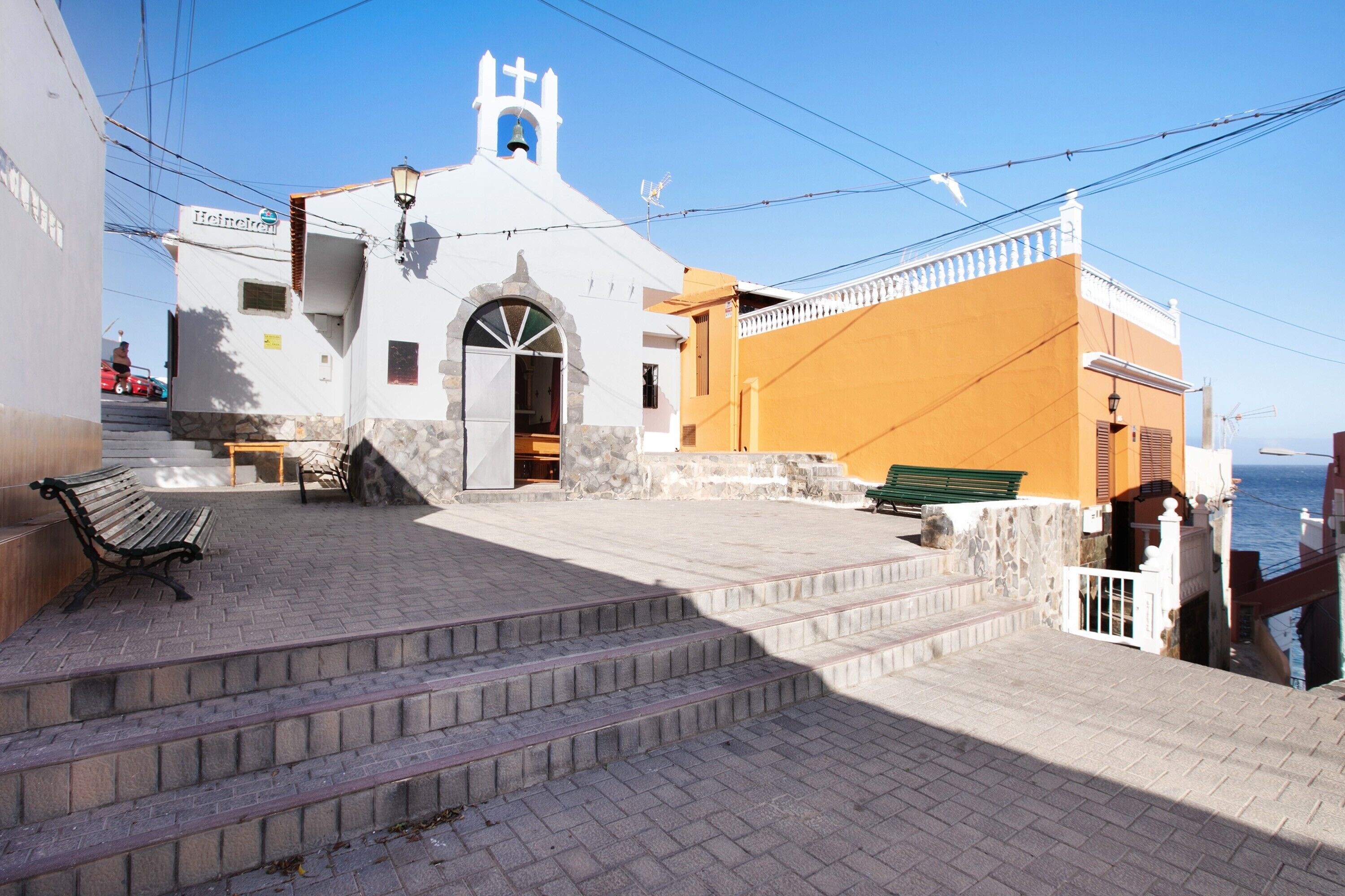Una iglesia con un campanario, escalones que llevan a ella y un banco a la izquierda.