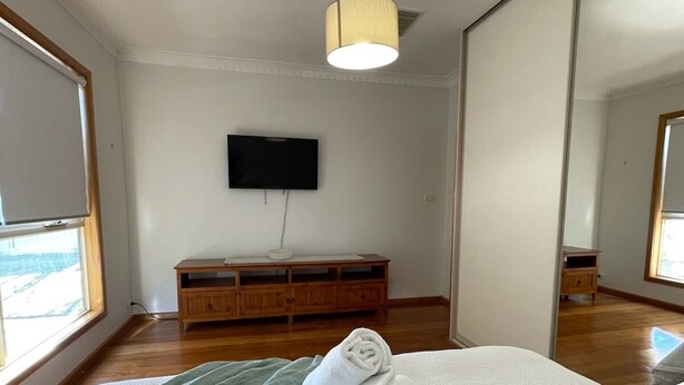 Habitación de hotel con cama, cómoda de madera, televisor de pantalla plana y espejo grande.