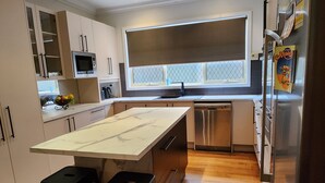 Una cocina moderna con una isla grande, electrodomésticos de acero inoxidable y piso de madera.