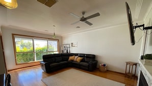 Una sala de estar con un sofá modular, una chimenea y un ventanal con vistas a zonas verdes.